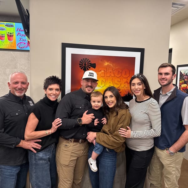 Three generations of a family, including a baby, posing in a Taco Casa restaurant.